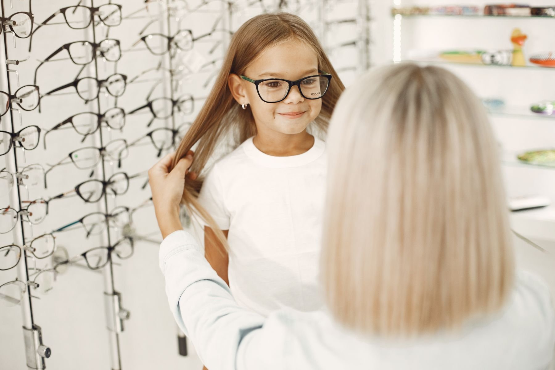 Bambina che prova gli occhiali da vista in negozio